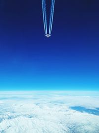 Aerial view of snowcapped mountains against clear blue sky