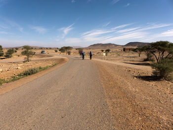 Rear view of people on road against sky