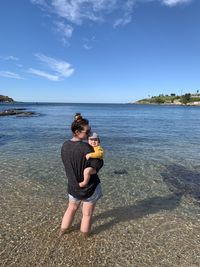 Full length of mother and baby at beach against sky