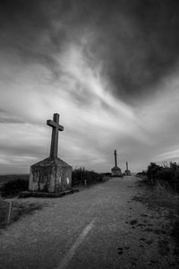 Cross on cemetery against sky