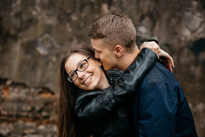 Loving boyfriend whispering in cheerful girlfriend ear outdoors