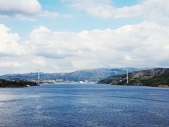 View of suspension bridge over river against cloudy sky