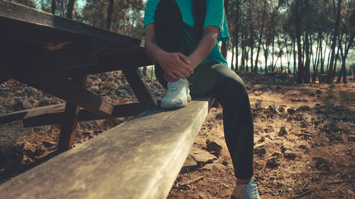 Low section of person on log in forest