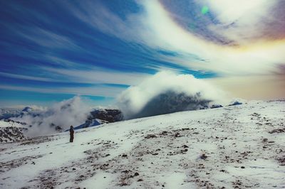 Person standing on snow covered landscape against sky