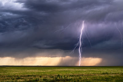 Lightning on field against storm clouds