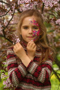 Spring portrait of a six year old girl standing under the blooming pink cherry tree