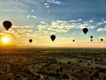 Hot air balloon flying over field against sky during sunset