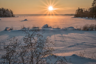 Scenic view of frozen lake against sky during sunset