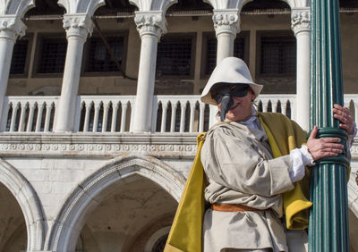 Portrait of man wearing hat standing against built structure