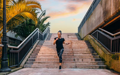 Female runner training down stairs over in urban runway on sunset