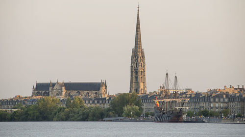 Buildings by river against sky in city bordeaux