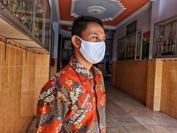 Portrait of a man standing at home in a mask