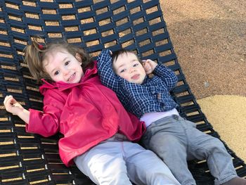 High angle view of siblings relaxing on hammock