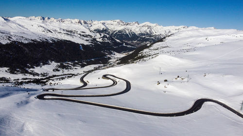 Scenic view of snowcapped mountains with winding road against sky