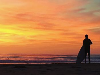 Silhouette man on beach against sky during sunset