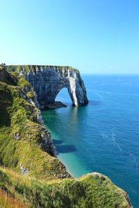 Rock formations in sea against clear blue sky