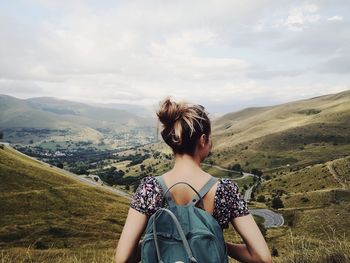 Rear view of woman looking at mountains against sky