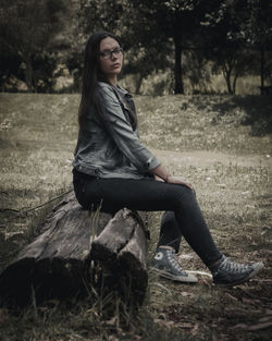 Side view of young woman sitting on field