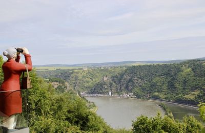 Scenic view of river by mountains against sky