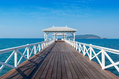 Pier over sea against clear blue sky