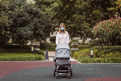 Full length of woman wearing mask while walking on footpath