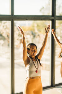 Smiling female coach exercising with arms raised at retreat center