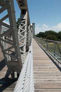 Footbridge over footpath against sky