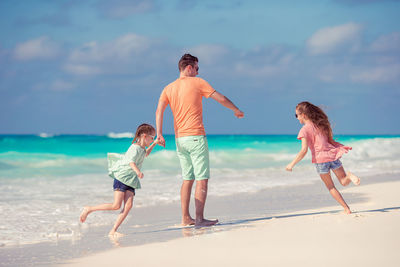 Full length of father and daughters on beach