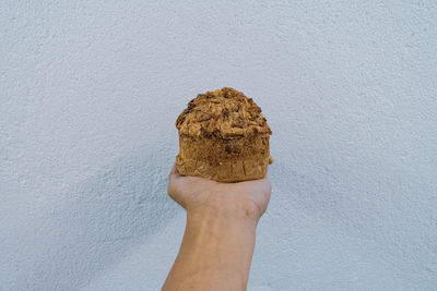 Close-up of hand holding ice cream cone against wall