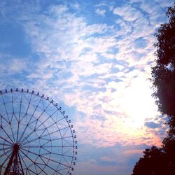 Low angle view of ferris wheel against cloudy sky