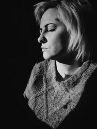 Close-up portrait of young woman against black background