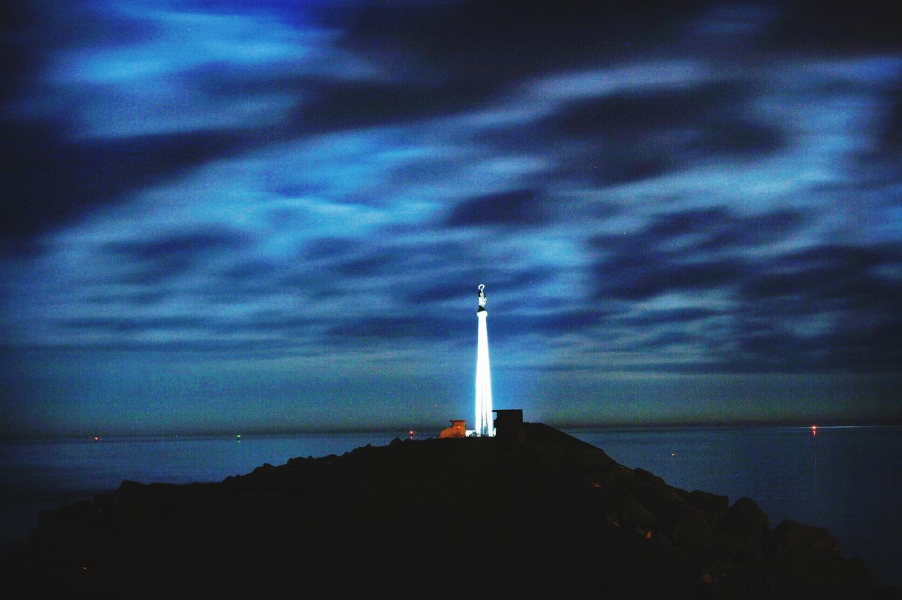 lighthouse, sea, guidance, sky, water, horizon over water, built structure, building exterior, cloud - sky, direction, nature, tranquility, architecture, scenics, beauty in nature, tranquil scene, cloud, outdoors, dusk, cloudy