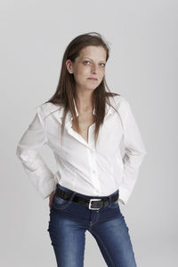 Portrait of young woman standing against white background
