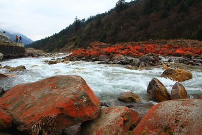 River flowing by rocks against sky