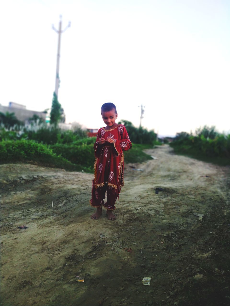 one person, nature, full length, sky, childhood, clothing, front view, child, day, standing, men, looking at camera, land, landscape, outdoors, adult, portrait, leisure activity, copy space, plant, environment, lifestyles, extreme sports, architecture, smiling, holding, dirt, emotion