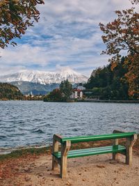 Bench by lake bled against autumn sky.