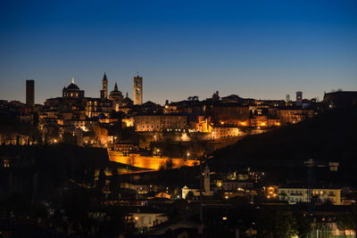 Illuminated cityscape against sky at night