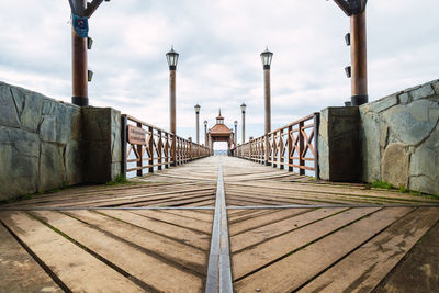 Rear view of person on footbridge against sky