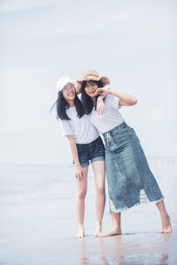 Friends enjoying at beach against sky