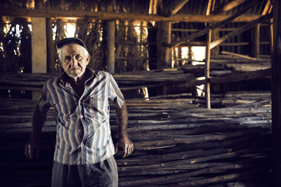 Portrait of man standing by firewood in factory