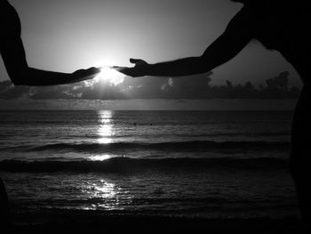 Silhouette people enjoying in sea against sky during sunset