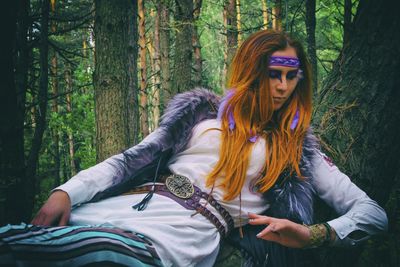 Redhead woman lying on tree trunk in forest