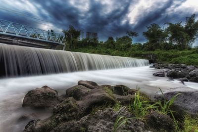 Water flowing in dam against sky