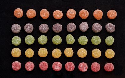 High angle view of colorful candies arranged on black background