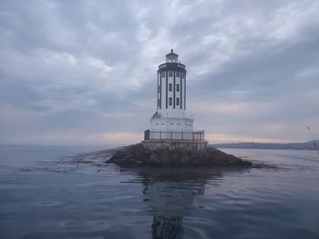 Lighthouse by sea against sky