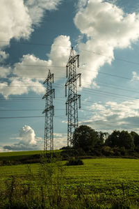 Electricity pylon on field against sky