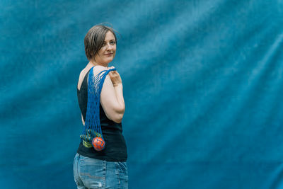 Portrait of young woman standing against yellow background