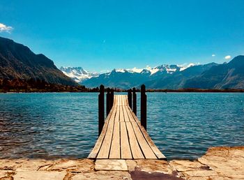 Scenic view of lake and mountains against clear blue sky