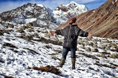 Man standing on rock against snowcapped mountains
