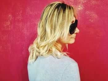 Portrait of young woman against red background